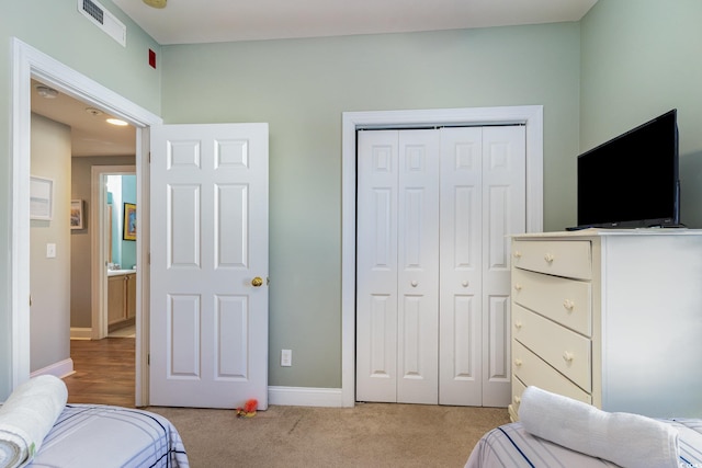 bedroom featuring light colored carpet, a closet, visible vents, and baseboards