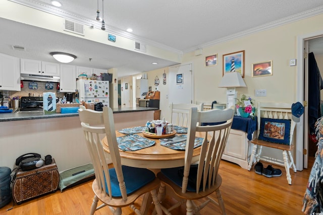 dining space with ornamental molding, a textured ceiling, visible vents, and light wood-style floors