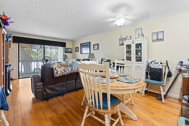dining space featuring crown molding, light wood-type flooring, ceiling fan, and a textured ceiling