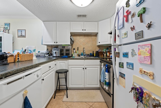 kitchen featuring a sink, white appliances, visible vents, and white cabinets