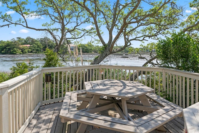 deck with a water view and outdoor dining space