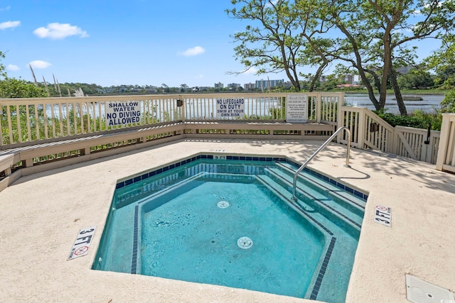 view of pool featuring a patio, a water view, and a hot tub