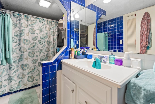 full bath featuring tile walls, vanity, a textured ceiling, and a shower with shower curtain
