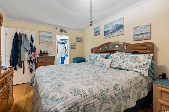 bedroom featuring a textured ceiling, visible vents, wood finished floors, and ornamental molding