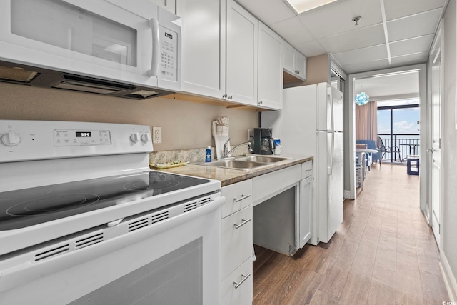 kitchen with white appliances, a sink, white cabinetry, light wood-style floors, and light countertops