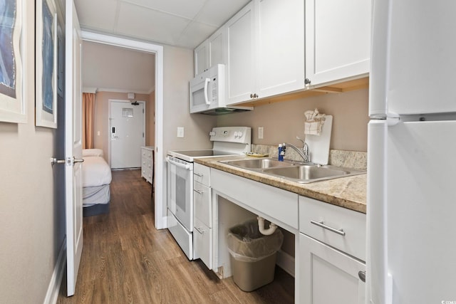 kitchen with white appliances, a sink, wood finished floors, white cabinetry, and light countertops