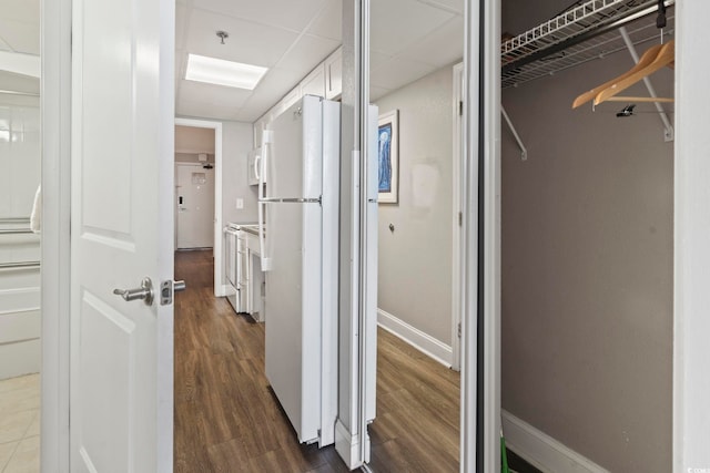 corridor featuring dark wood-type flooring and baseboards