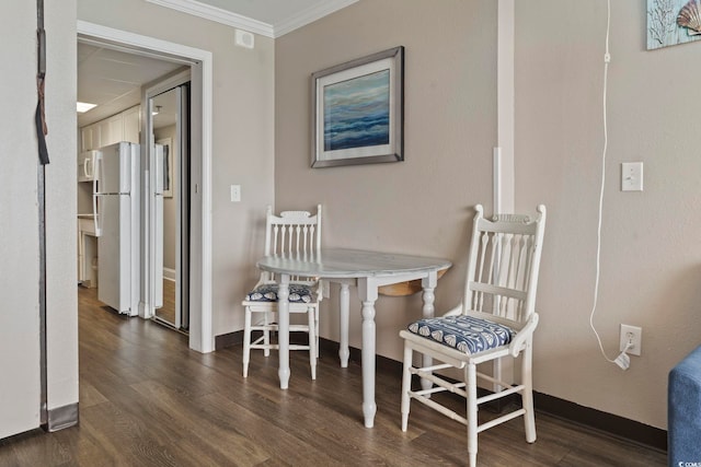 dining room featuring wood finished floors, crown molding, and baseboards