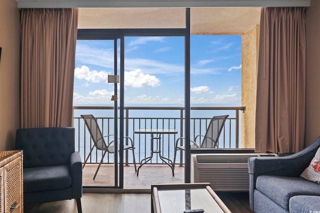 living area with wood finished floors, a water view, and floor to ceiling windows
