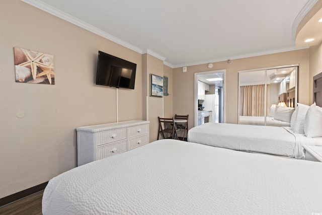 bedroom featuring ornamental molding, dark wood-type flooring, baseboards, and connected bathroom