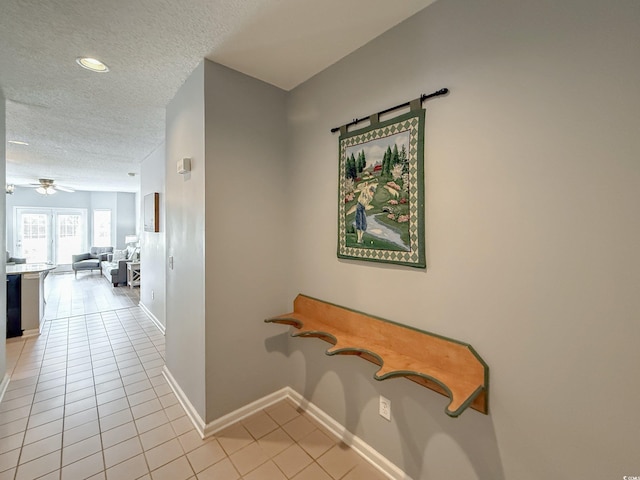hallway featuring baseboards, light tile patterned floors, recessed lighting, and a textured ceiling
