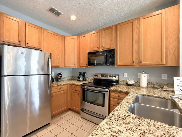 kitchen with light tile patterned floors, a sink, a textured ceiling, visible vents, and appliances with stainless steel finishes