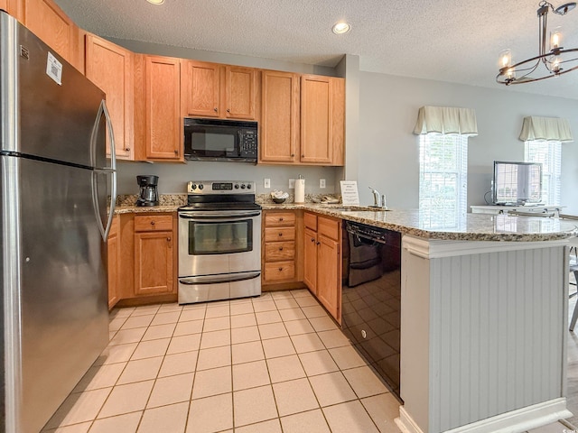 kitchen featuring a peninsula, a sink, a textured ceiling, black appliances, and light stone counters