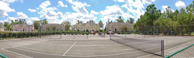 view of tennis court featuring fence and a residential view