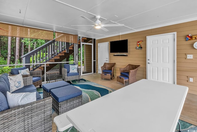 living room featuring ceiling fan and wood walls