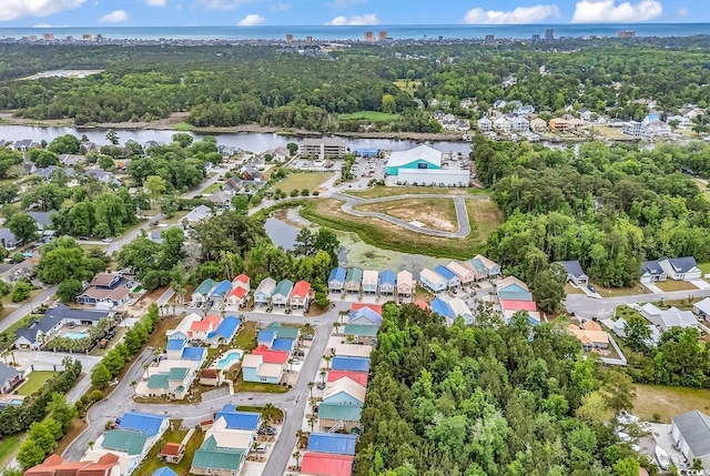 aerial view of property's location with a large body of water, nearby suburban area, and a tree filled landscape