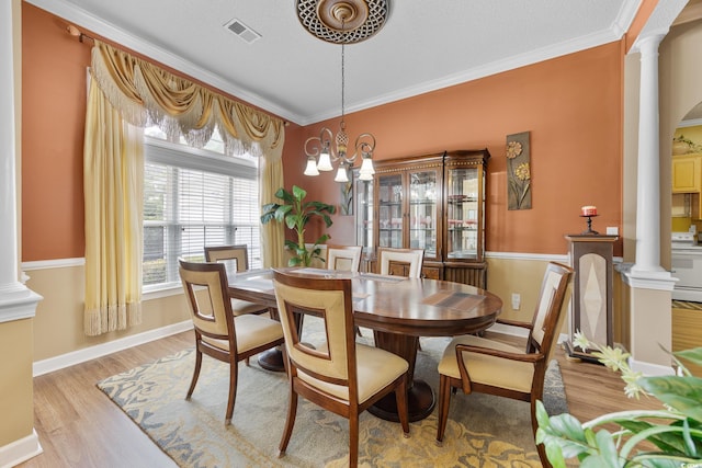 dining room featuring ornate columns, light wood-type flooring, ornamental molding, and baseboards