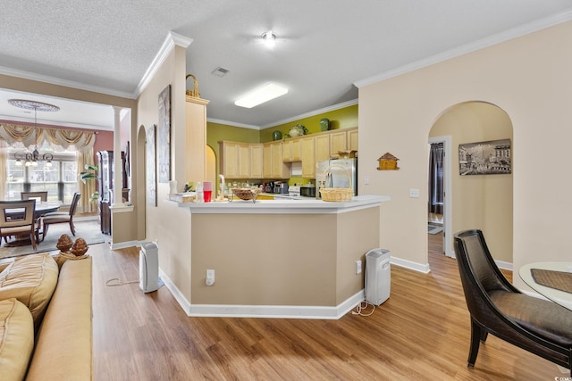 kitchen with stainless steel fridge, light brown cabinetry, light wood-style flooring, crown molding, and a chandelier