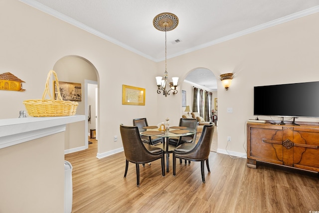 dining room with arched walkways, a chandelier, light wood-type flooring, ornamental molding, and baseboards