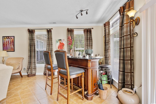 indoor dry bar featuring a textured ceiling, light tile patterned flooring, crown molding, and baseboards
