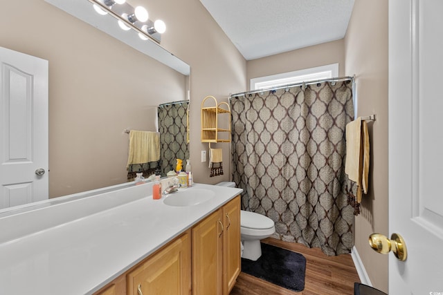 bathroom featuring wood finished floors, toilet, vanity, a textured ceiling, and curtained shower