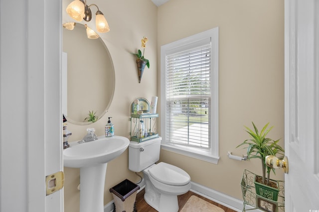 bathroom with toilet, baseboards, and a chandelier