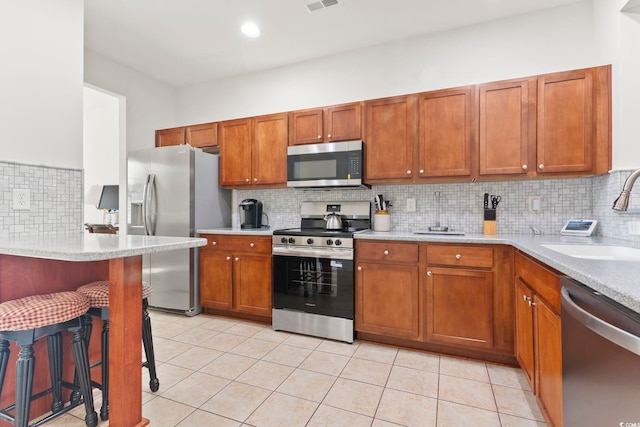 157 Olde Towne Way Unit 4, Myrtle Beach, SC 29588 - kitchen with light tile patterned floors, a sink, a kitchen breakfast bar, backsplash, and appliances with stainless steel finishes