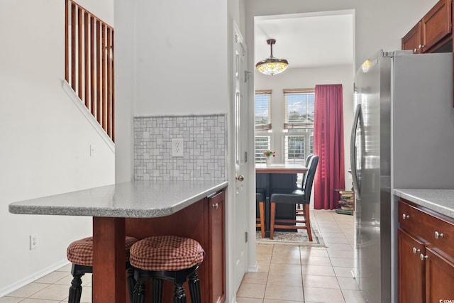 157 Olde Towne Way Unit 4, Myrtle Beach, SC 29588 - kitchen with a peninsula, light tile patterned floors, a kitchen bar, freestanding refrigerator, and tasteful backsplash