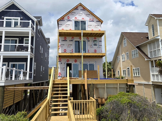 rear view of house featuring board and batten siding and stairs