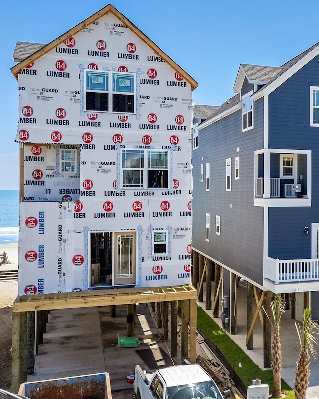 back of property with roof with shingles and a water view