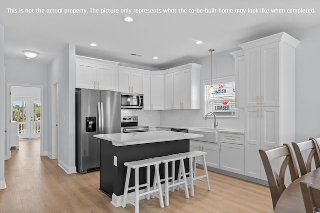 kitchen with light wood finished floors, appliances with stainless steel finishes, a sink, and a kitchen island