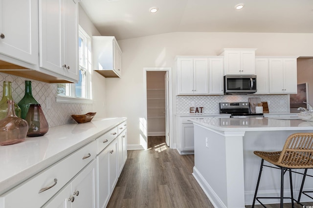 725 Choctaw Dr, Conway, SC 29526 - kitchen featuring appliances with stainless steel finishes, dark wood-type flooring, a kitchen breakfast bar, light countertops, and decorative backsplash