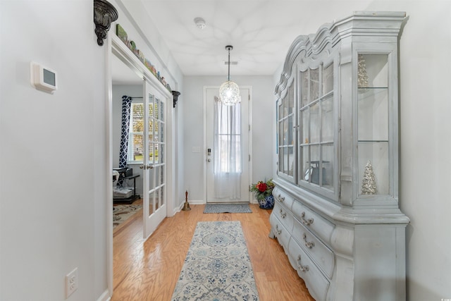 foyer entrance featuring baseboards, light wood finished floors, and french doors