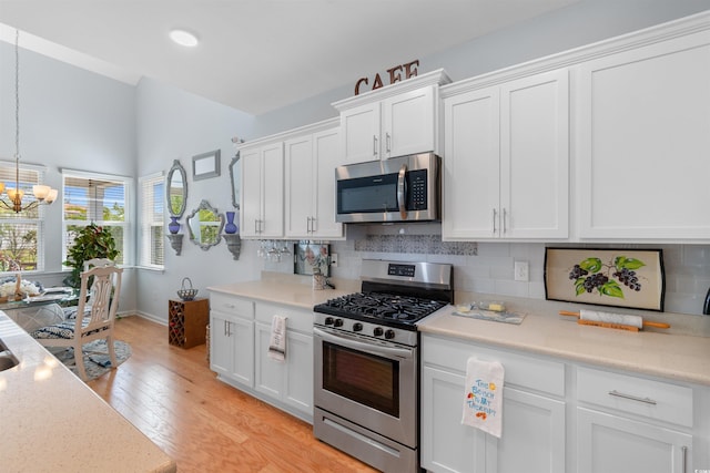 kitchen featuring white cabinetry, stainless steel appliances, an inviting chandelier, and tasteful backsplash