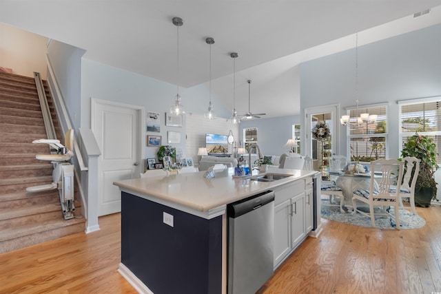 kitchen with light wood finished floors, a sink, open floor plan, white cabinetry, and dishwasher