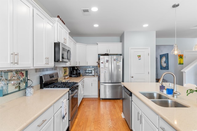 kitchen featuring white cabinetry, stainless steel appliances, visible vents, and a sink