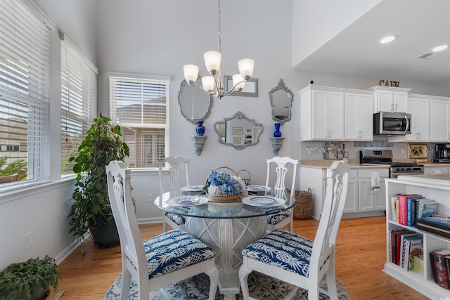 dining room featuring a chandelier, recessed lighting, a high ceiling, and light wood-style floors