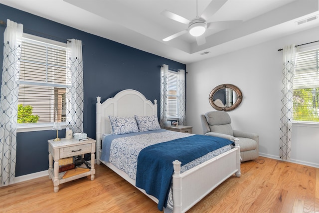 bedroom with light wood-style floors, visible vents, baseboards, and ceiling fan