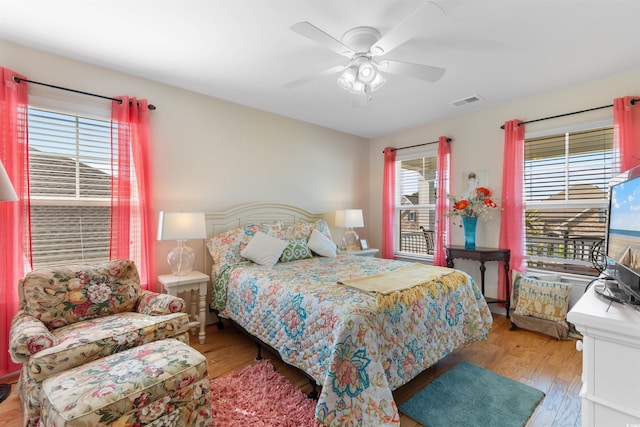 bedroom featuring a ceiling fan, visible vents, and wood finished floors
