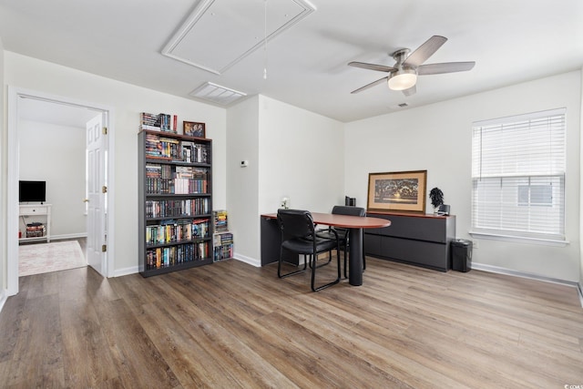 office space featuring wood finished floors, attic access, visible vents, baseboards, and ceiling fan
