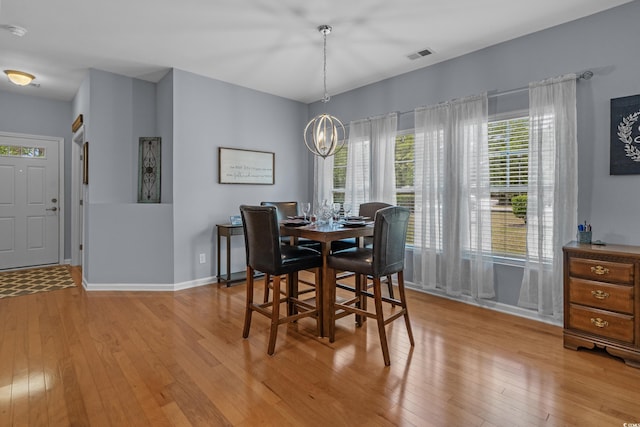 dining space with light wood-style floors, a chandelier, and baseboards
