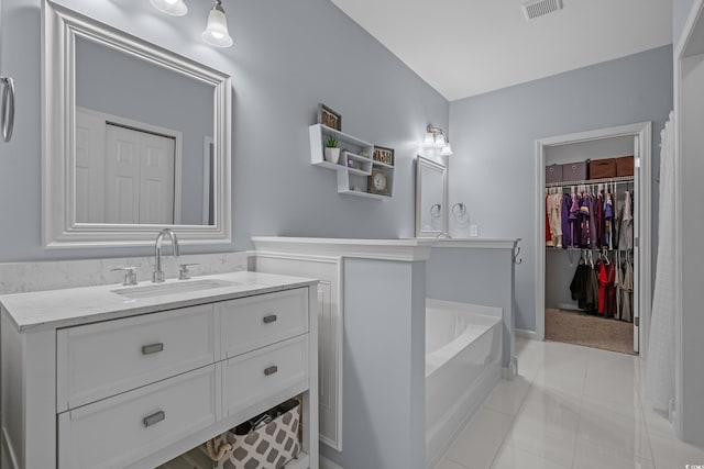 full bath featuring tile patterned floors, vanity, a bath, and a spacious closet
