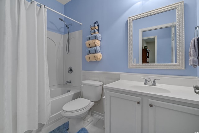 full bathroom with shower / bathtub combination with curtain, a wainscoted wall, toilet, and vanity