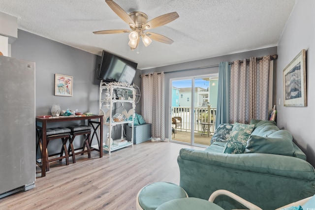 living room featuring a textured ceiling, wood finished floors, and ceiling fan