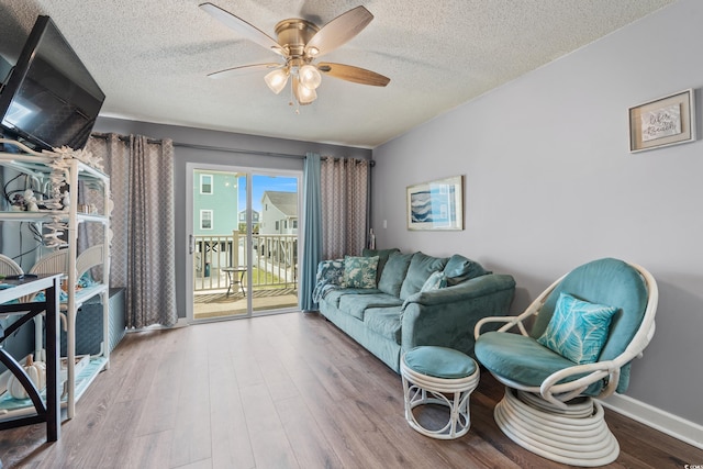 living room with a textured ceiling, wood finished floors, baseboards, and ceiling fan