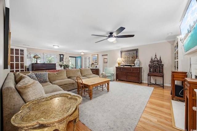 living room with french doors, light wood-style flooring, baseboards, ceiling fan, and ornamental molding