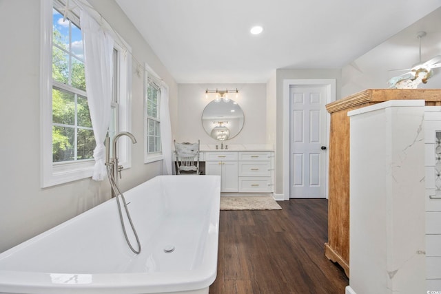 bathroom with wood finished floors, vanity, recessed lighting, a ceiling fan, and a freestanding bath