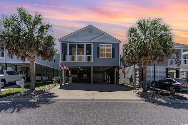 raised beach house featuring a carport, driveway, and a sunroom