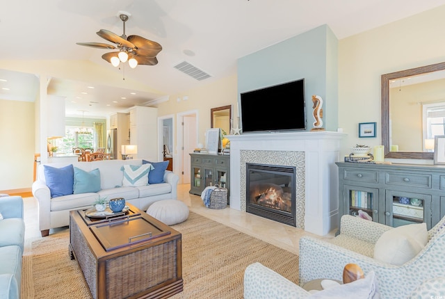 living area with plenty of natural light, ceiling fan, a tile fireplace, and vaulted ceiling