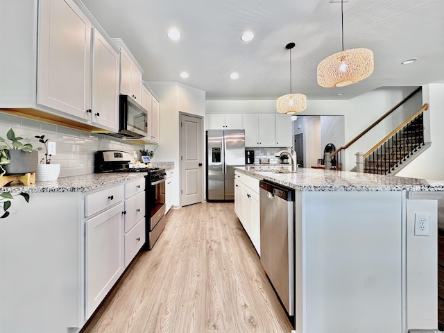 kitchen with stainless steel appliances, a sink, white cabinets, an island with sink, and recessed lighting